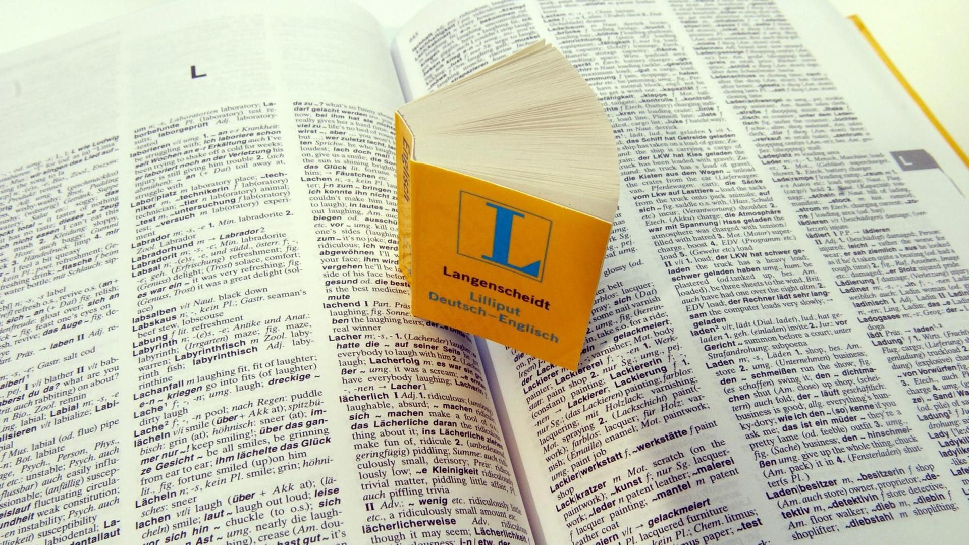Ein Miniatur-Wörterbuch "Deutsch - Englisch" steht auf den aufgeschlagenen Seiten seines großen "Bruders"
