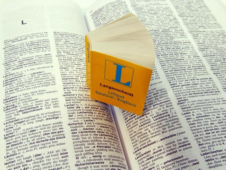 Ein Miniatur-Wörterbuch "Deutsch - Englisch" steht auf den aufgeschlagenen Seiten seines großen "Bruders"