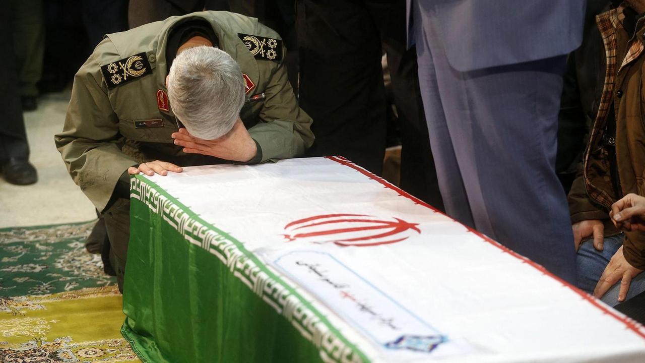 Bei der Beerdigung von General Soleimani beugt sich ein trauernder Mann über dessen Sarg.  

