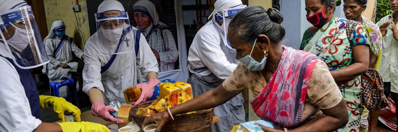 Indien, Kolkata: Nonnen des katholischen Ordens "Missionarinnen der Nächstenliebe", gegründet von Mutter Teresa, tragen Mundschutze und Gesichtsschutze bei der Verteilung von Nahrungsmittel an arme und obdachlose Menschen. 