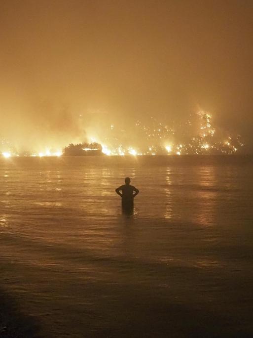 Ein Mann beobachtet die Flammen, als sich ein Waldbrand dem Strand von Kochyli auf der Insel Evia nähert.