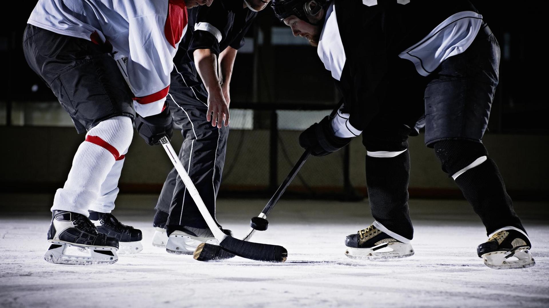 Zwei Eis-Hockey-Spieler kämpfen um den Puck.