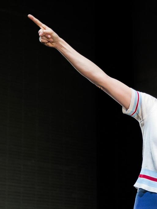 Julischka Eichel steht mit einem anklagenden Ausdruck und erhobenem Arm auf der Bühne.