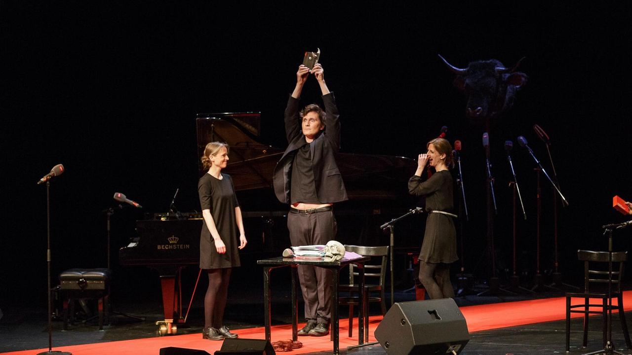 Der Kabarettist Hosea Ratschiller hält die Auszeichnung "Salzburger Stier 2017" mit ausgestreckten Armen in die Höhe. Links und rechts neben ihm stehen die Zwillingsschwestern Birgit und Nicole Radeschnig vom Musik-Kabarett-Duo RaDeschnig.