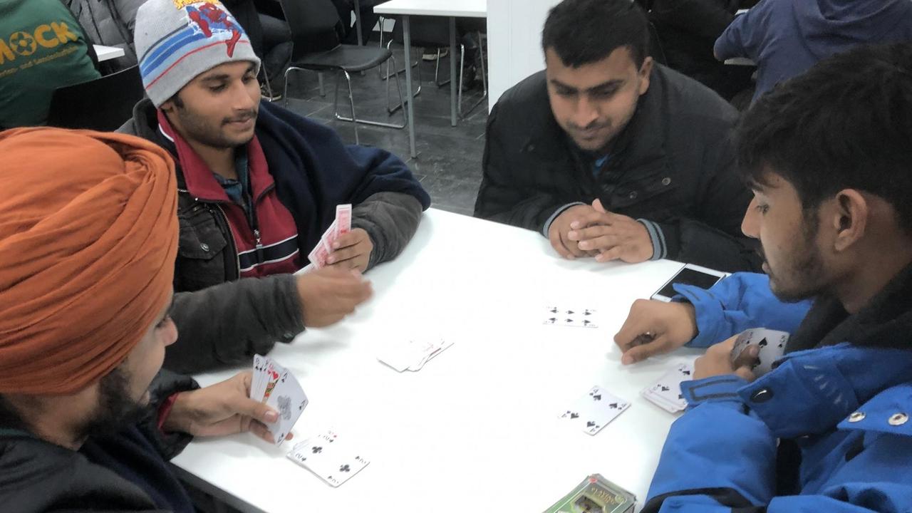Flüchtlinge spielen Karten an einem Tisch