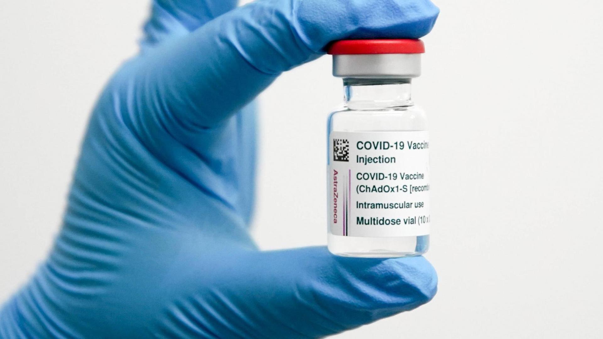 Im Bild ist eine Dose mit dem Covid-19 Impfstoff von Astra Zeneca gehalten von einer Hand in einem Gummihandschuh zu sehen.