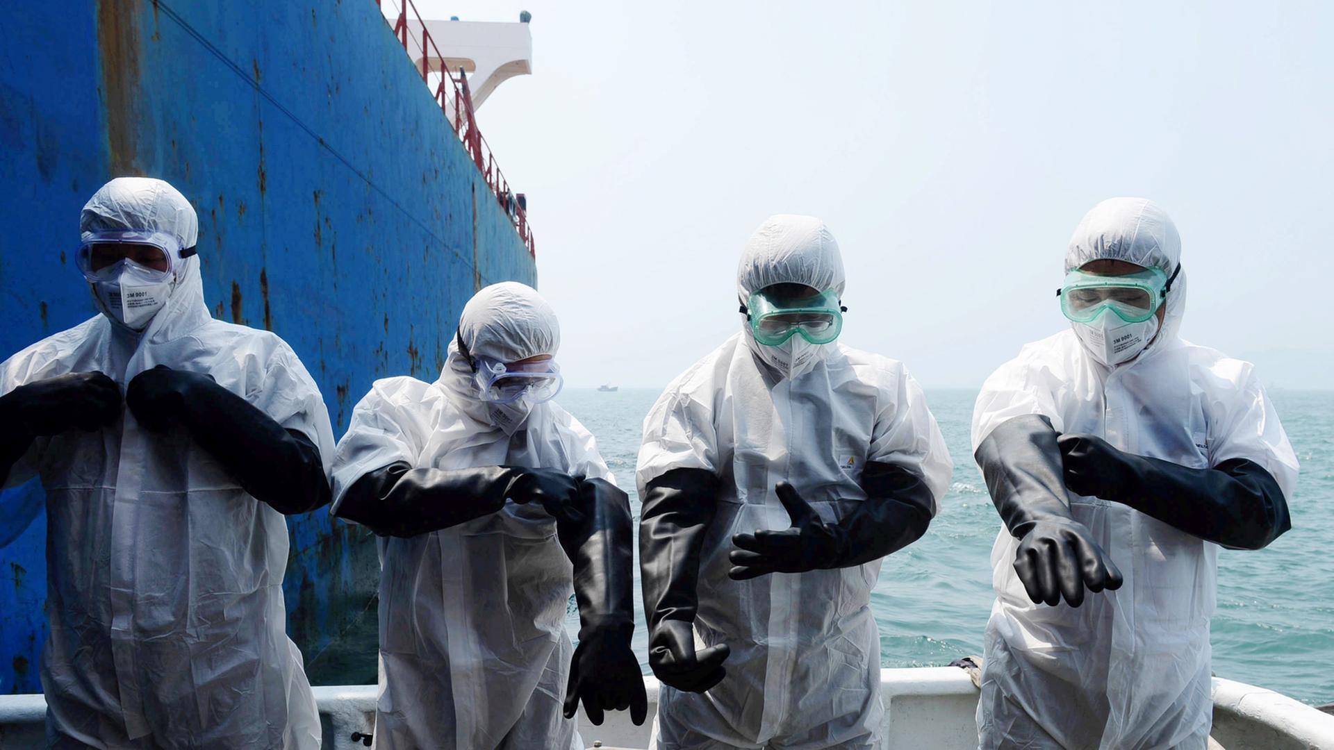 Chinesische Quarantäne-Arbeiter inspizieren ein Schiff aus Sierra Leone