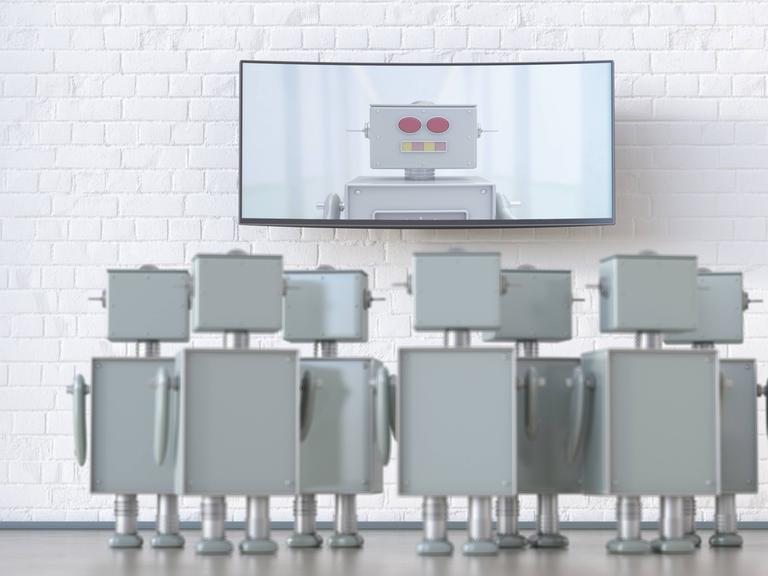 Eine Gruppe von Robotern blickt auf einen Bildschirm mit einem Roboter