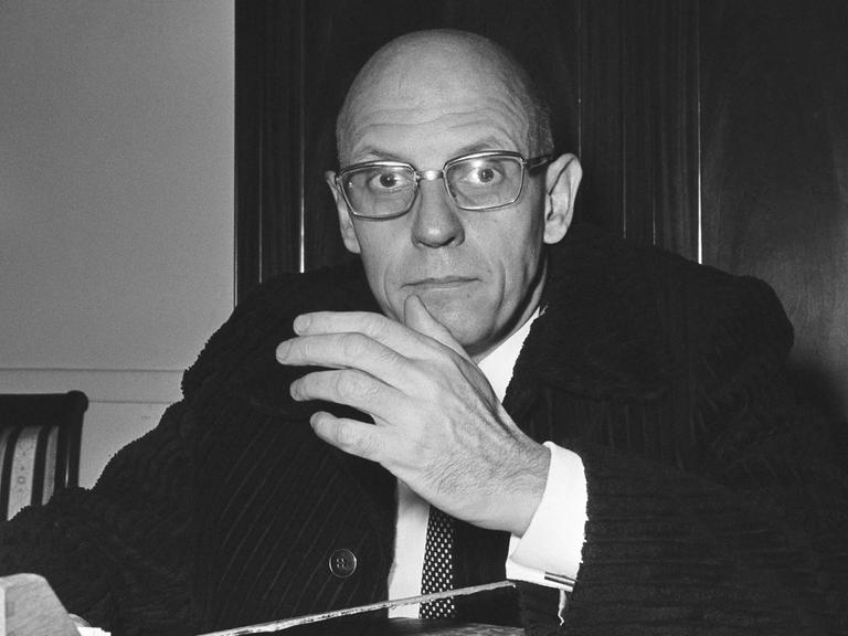 Michel Foucault sitzt an seinem Schreibtisch und schaut erstaunt in die Kamera. Aufgenommen in Paris 1970.