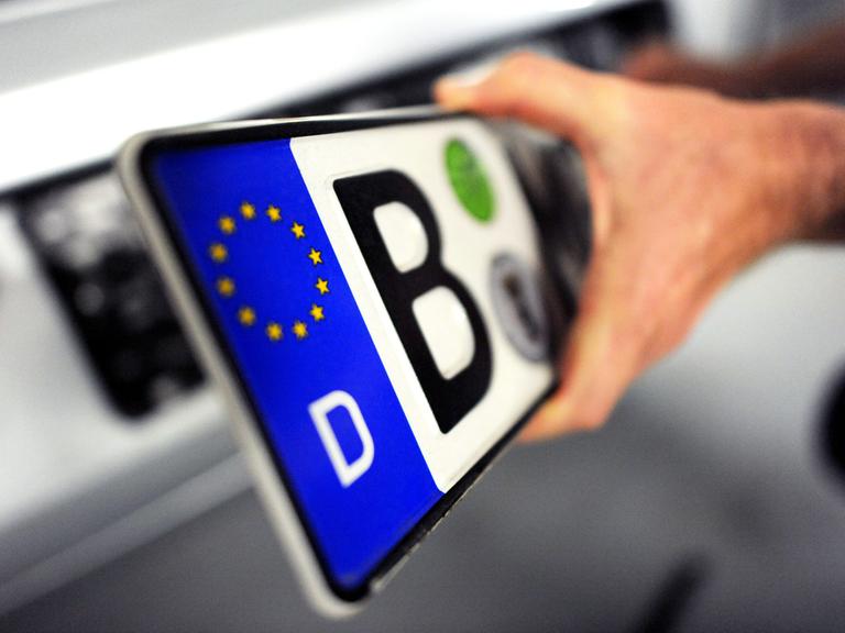 Ein Mann hat am Freitag in Berlin ein Nummernschild in der Hand, das er zuvor von einem Auto abmontiert hatte.