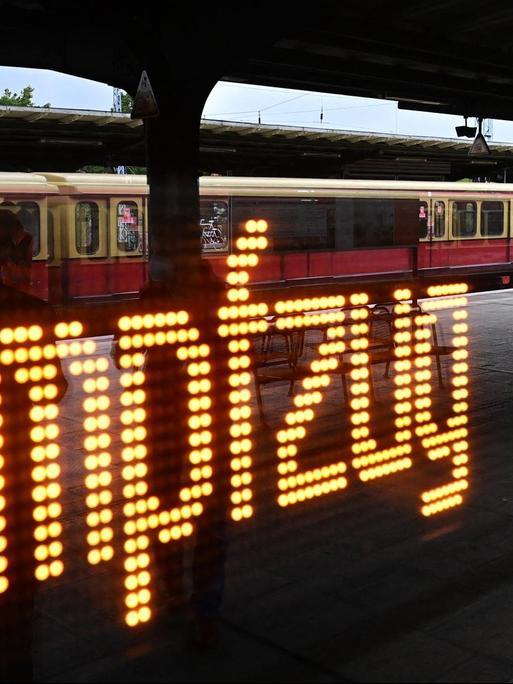 Hinter einem Fenster der Berliner S-Bahn leuchtet das Wort "Impfzug" auf, in der Spiegelung ist ein halb leerer Bahnsteig zu sehen.