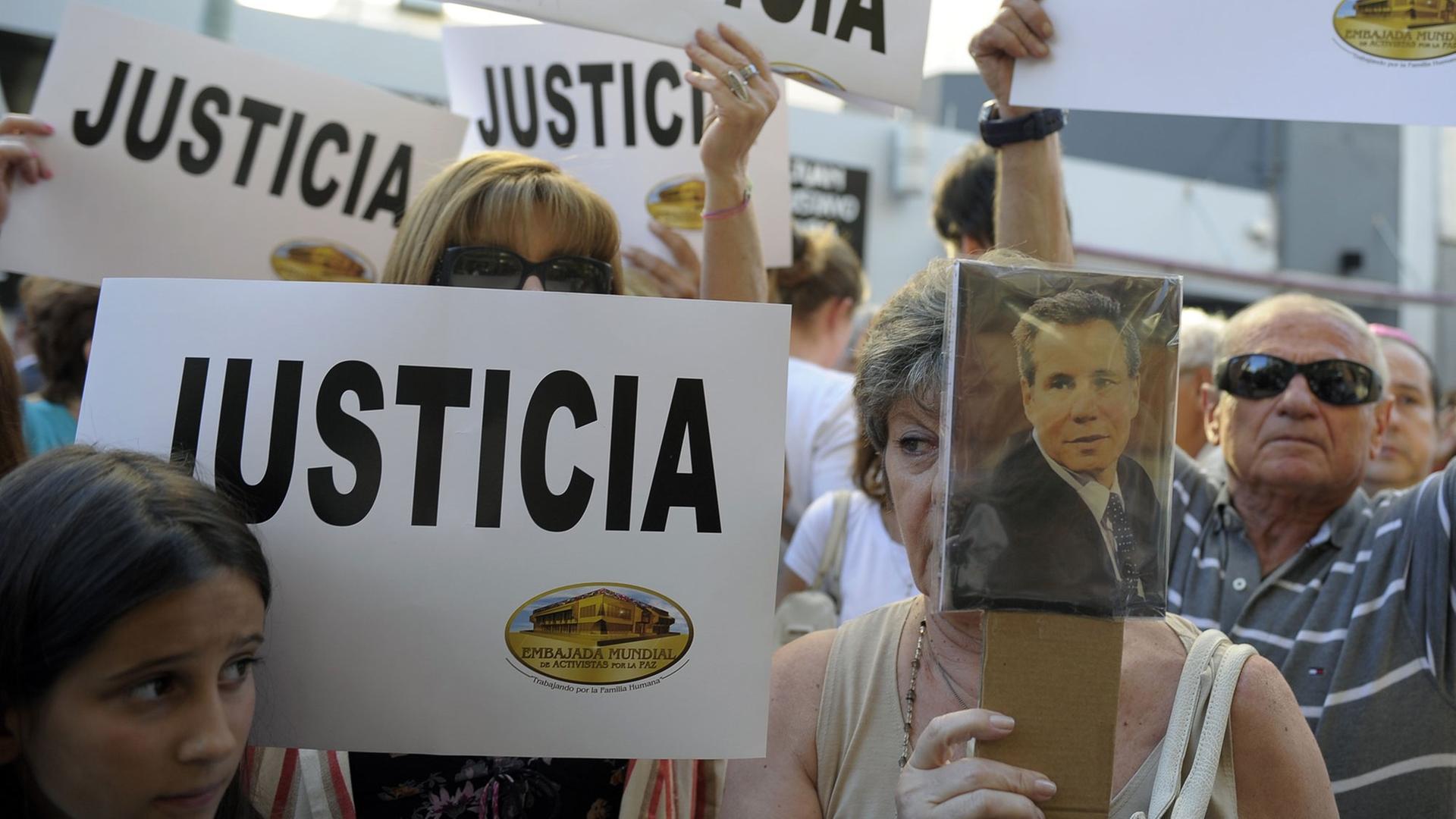 Menschen in Buenos Aires halten Plakate hoch - aus Protest gegen den mysteriösen Tod eines Staatsanwalts, der im Fall des Anschlags auf das jüdische Gemeindezentrum Amia 1994 mit 85 Toten ermittelte.