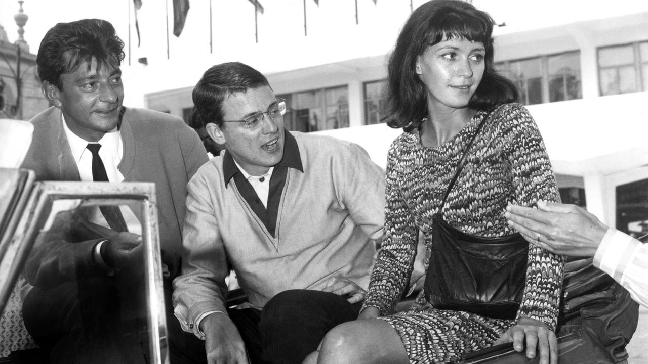 Der Regisseur des Films "Abschied von gestern" Alexander Kluge (M), der Drehbuchautor Günther Mack (l) und die Schauspielerin Alexandra Kluge (r) in einem Cabrio während des Filmfestivals in Venedig 1966.
