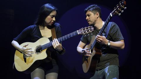 Ein Mann und eine Frau spielen Gitarre.