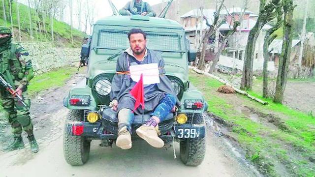 Farooq Ahmad Dar, gefesselt auf einem Armee-Jeep auf einem Weg, links daneben ein bewaffneter Soldat