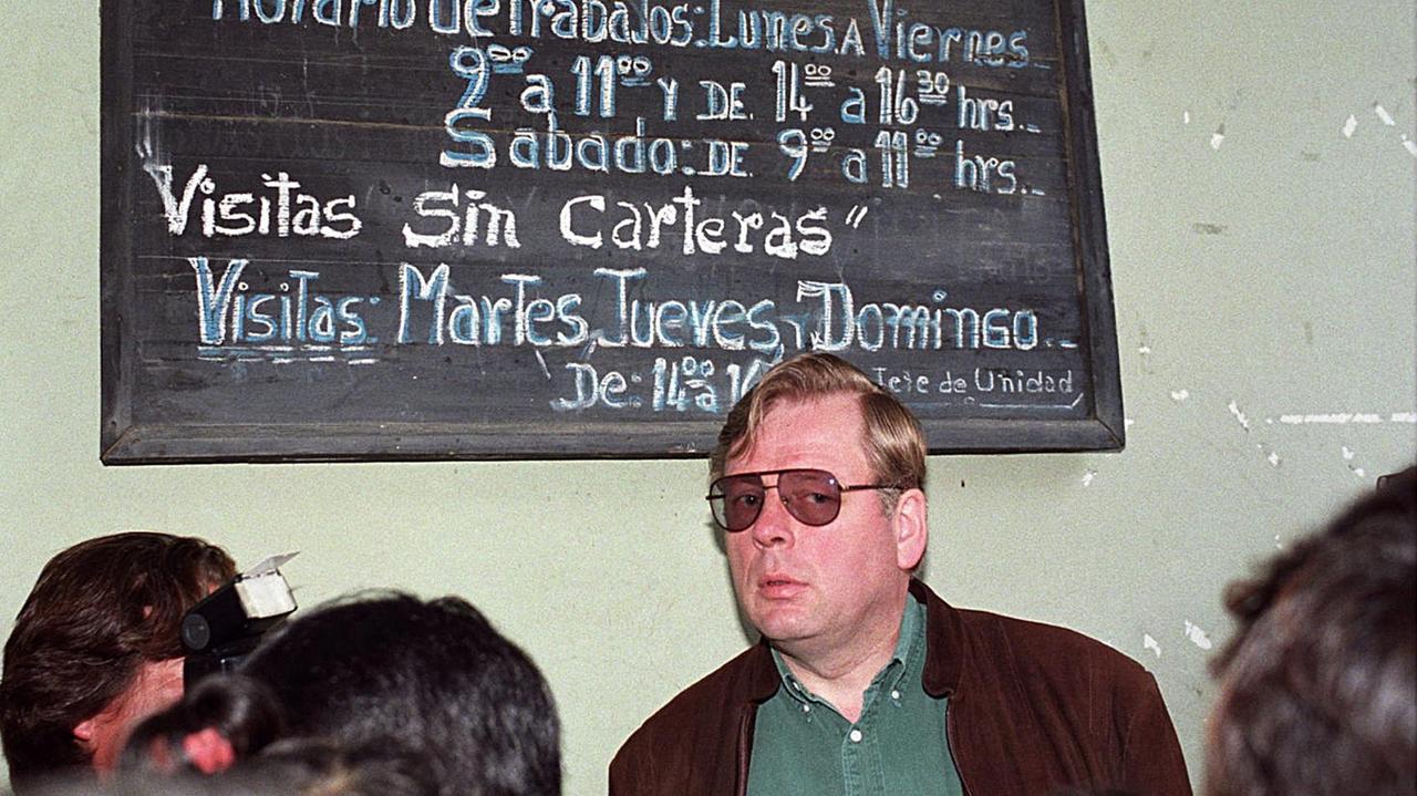 Hartmut Hopp steht mit Sonnenbrille vor einer Tafel