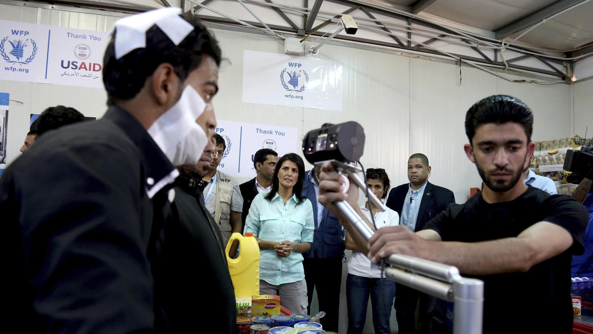 Die US-Botschafterin bei den Vereinten Nationen, Nikki Haley (Hintergrund), beobachtet, wie ein bandagierter syrischer Flüchtling seine Iris am 21. Mai 2017 im Zaatari Flüchtlingslager in einem Supermarkt gescannt hat.