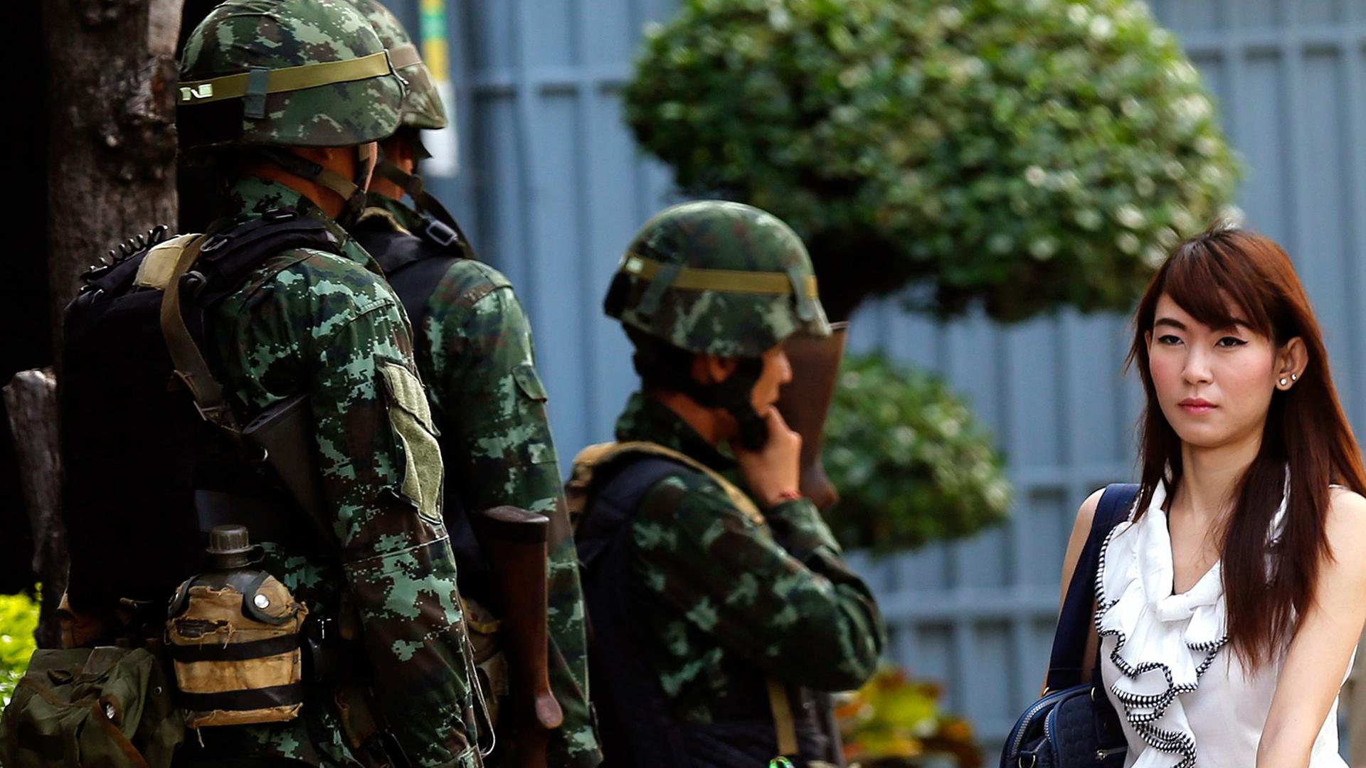 Straßenszene in Bangkok nach der Verhängung des kriegsrechts am Dienstag, eine Frau passiert mehrere Soldaten.