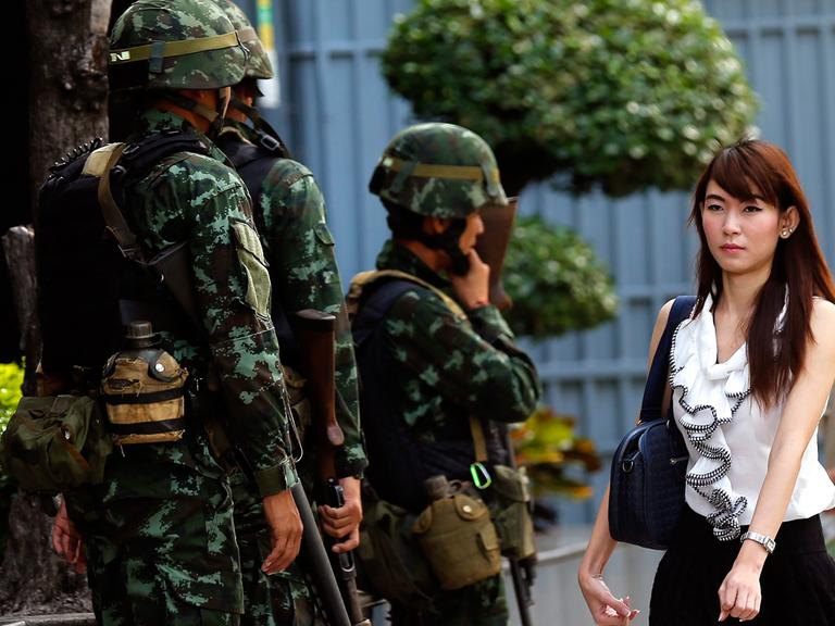 Straßenszene in Bangkok nach der Verhängung des kriegsrechts am Dienstag, eine Frau passiert mehrere Soldaten.