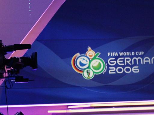 Eine Kamera steht vor einer Bühne mit dem Logo der Fußball-WM 2006.