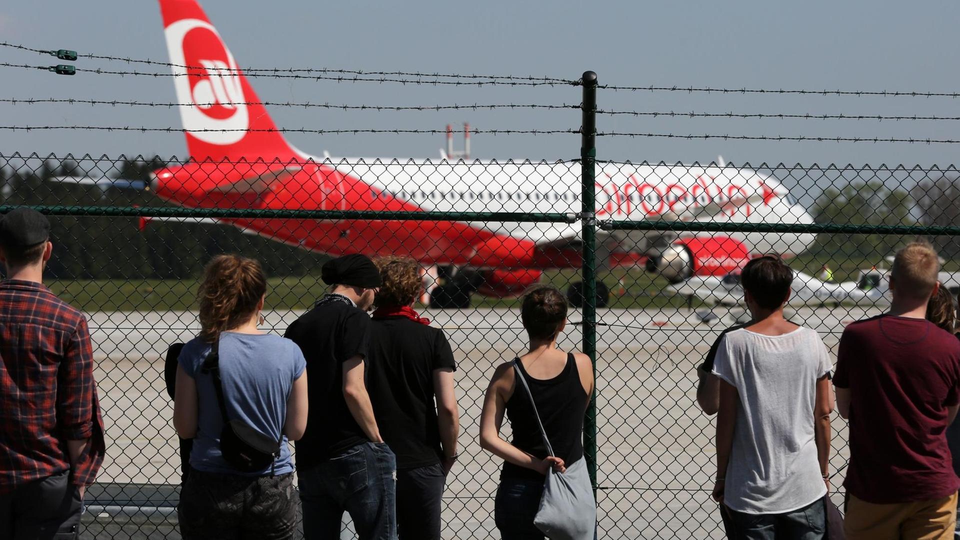 Am Flughafen Rostock-Lage startet eine Maschine mit abgeschobenen Asylbewerbern, Aktivisten schauen hinter einem Zaun zu.