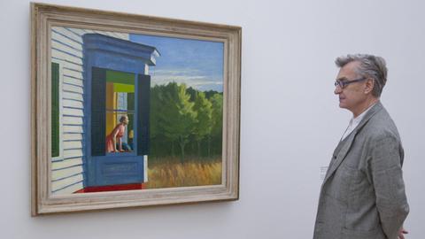 Das Bild zeigt Wim Wenders vor einem Bild von Edward Hopper in der Ausstellung in Basel.