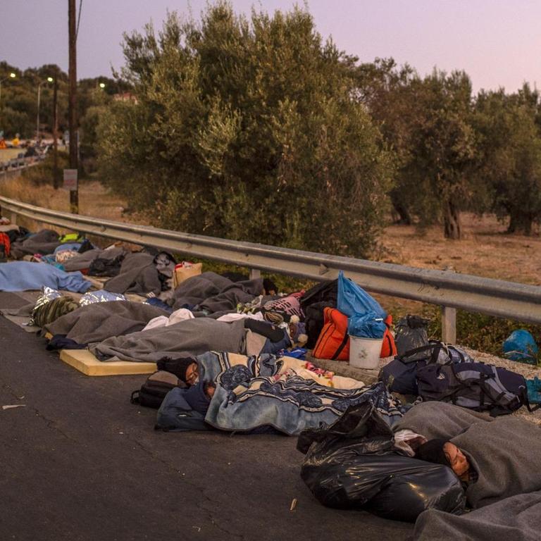 Migranten aus dem griechischem Flüchtlingscamp Moria schlafen am Straßenrand.
