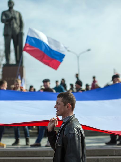 Unterstützer des Referendums in Simferopol auf der Krim tragen eine russische Flagge durch die Straße.
