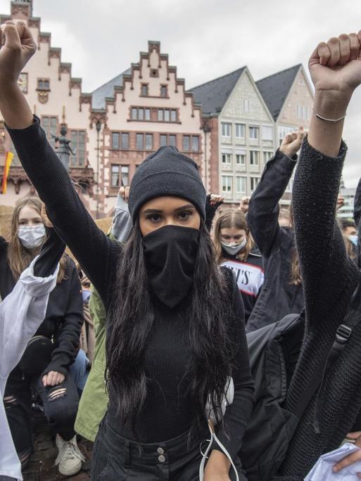 Auf Knien und mit in die Höhe gestreckter Faust bekunden Demonstrantinnen auf dem Römerberg in Frankfurt ihre Solidarität mit den Anti-Rassismus-Protesten in den USA.