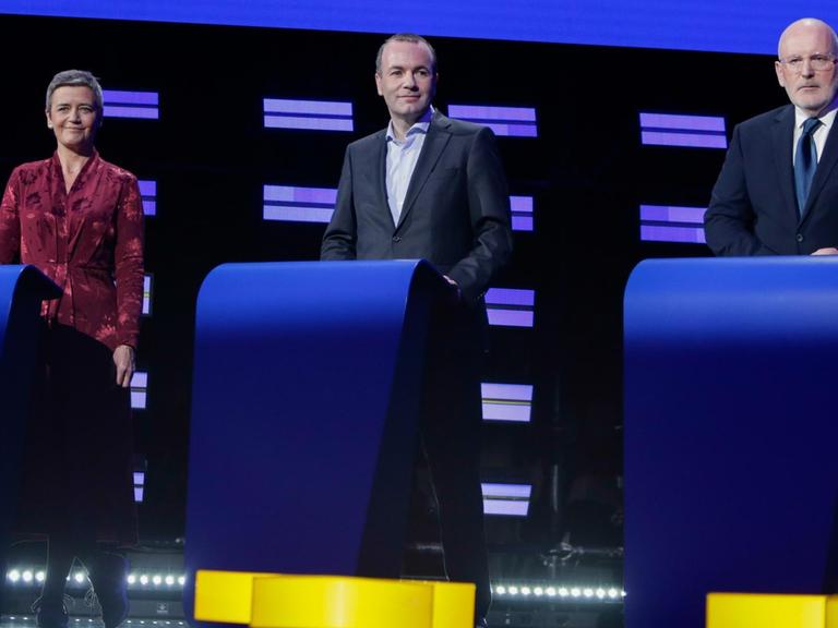 Margrethe Vestager, Manfred Weber und Frans Timmermans stehen nebeneinander jeweils hinter einem Pult auf einer Bühne