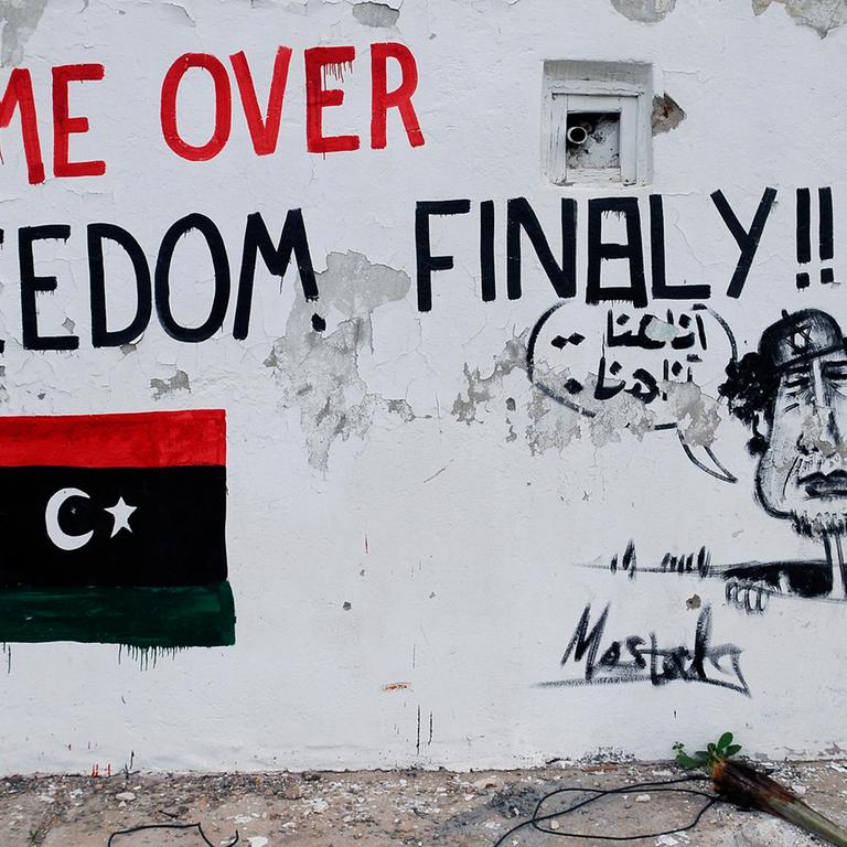     Bemalte Mauer in der libyschen Hauptstadt Tripolis: Zu sehen ist eine libysche Flagge in den Nationalfarben, die Aufschrift "Game over - Freedom finally" und ein Gaddafi, der aus einem Abfluss schaut und "hier bin ich, hier bin ich" ruft.