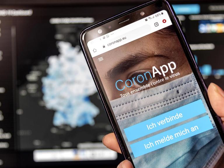 Die Freiwilige Corona-App "app.coronapp.eu" auf einem Handy-Display mit der Robert Koch Institut Website im Hintergrund.