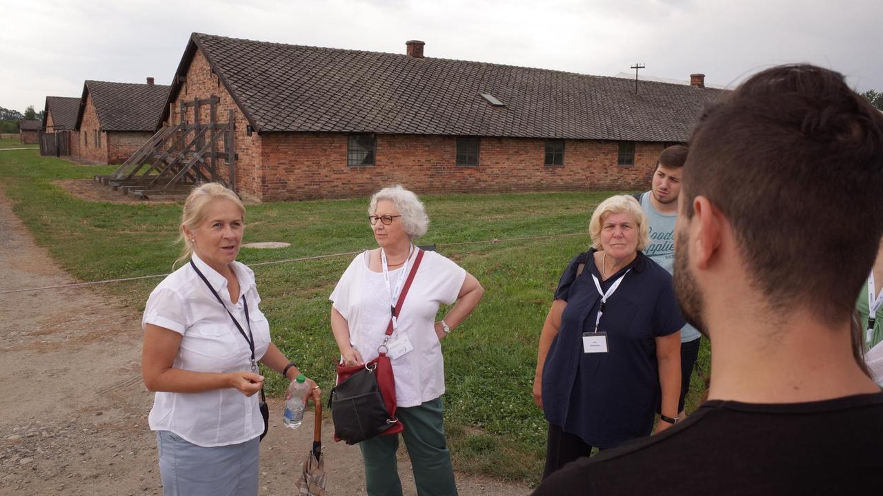 Die Fremdenführerin erzählt der Reisegruppe von Auschwitz Die Fremdenführerin erzählt der Reisegruppe von Auschwitz