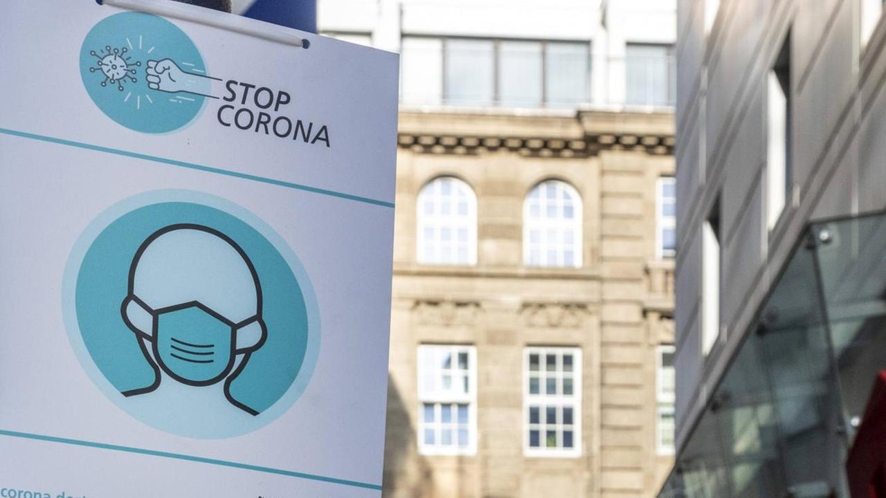 "Stop Corona" steht auf einem Hinweisschild in einer Fußgängerzone