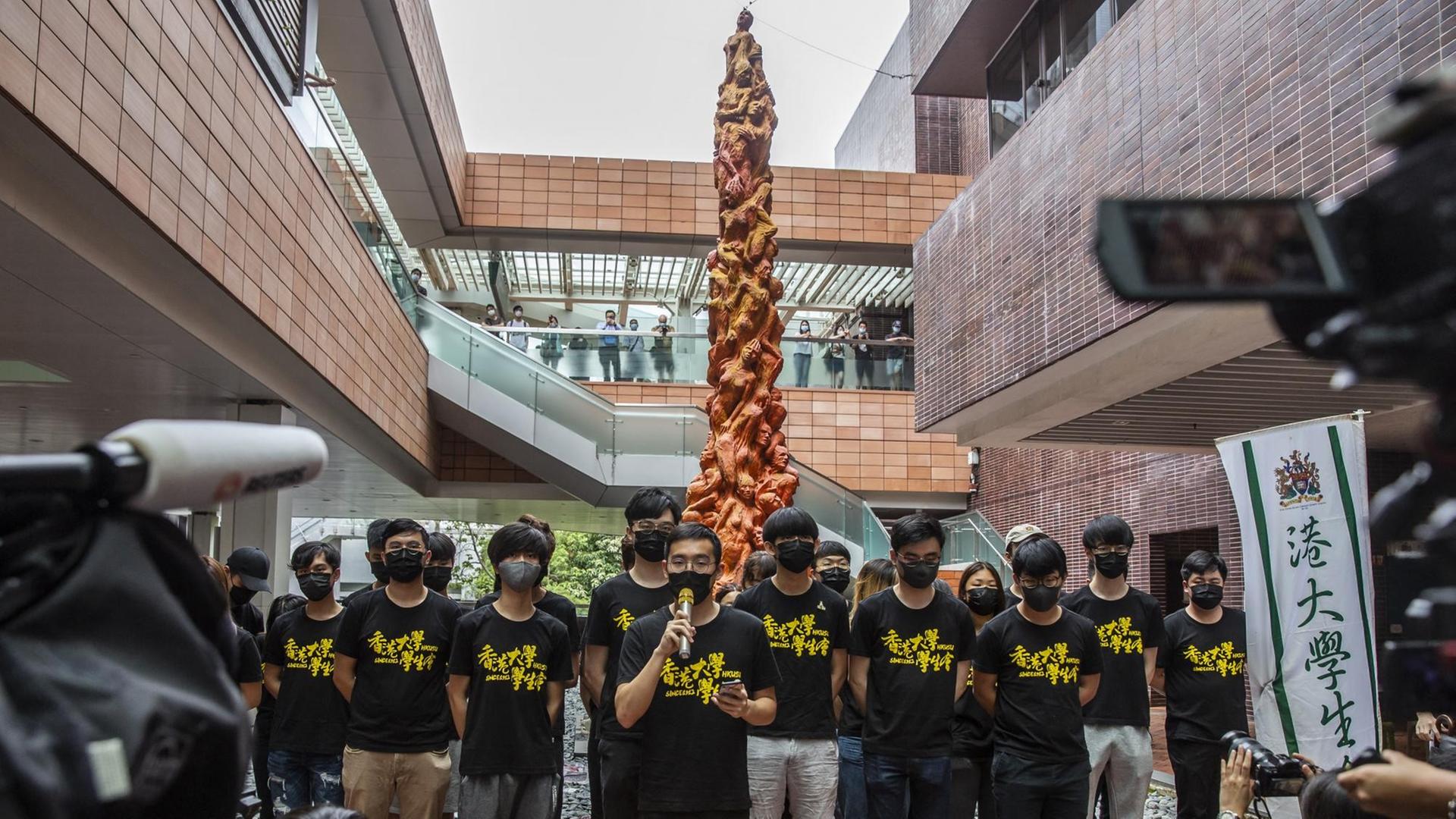 Studierende stehen vor der "Säule der Schande" auf dem Campus der Universität Hongkong. Sie erinnert an die blutige Niederschlagung der Demokratiebewegung in China 1989. Die Skulptur ist acht Meter hoch und zeigt geschundene menschliche Körper.