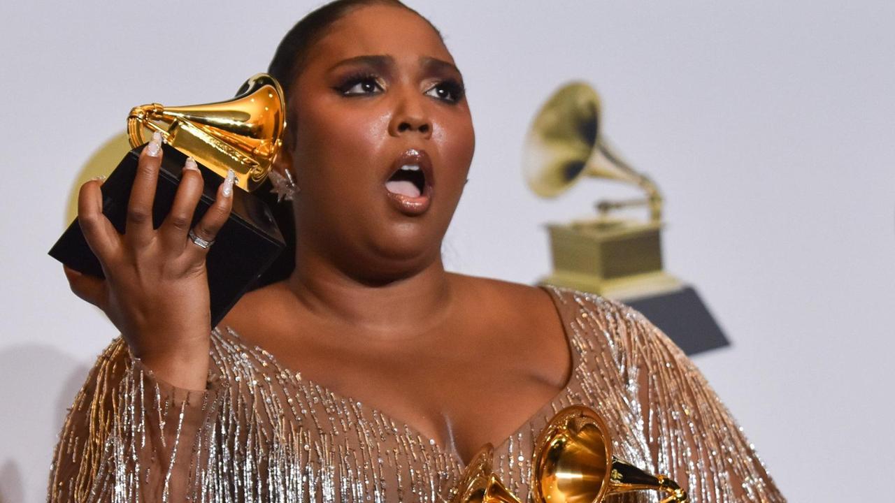 Lizzo posiert backstage bei den 62. Grammy Awards mit ihren drei Trophäen.