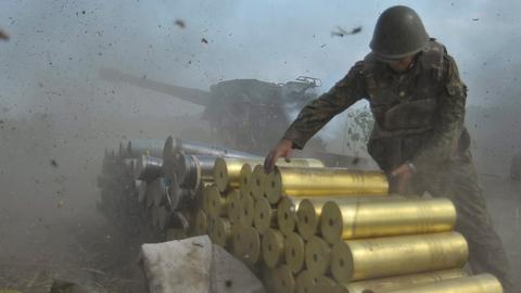 Ein ukrainischer Soldat in Lugansk neben einem Panzer. Er stapelt Patronen.