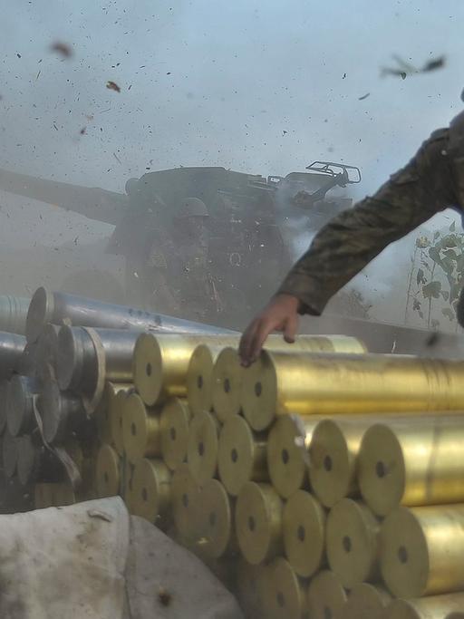 Ein ukrainischer Soldat in Lugansk neben einem Panzer. Er stapelt Patronen.