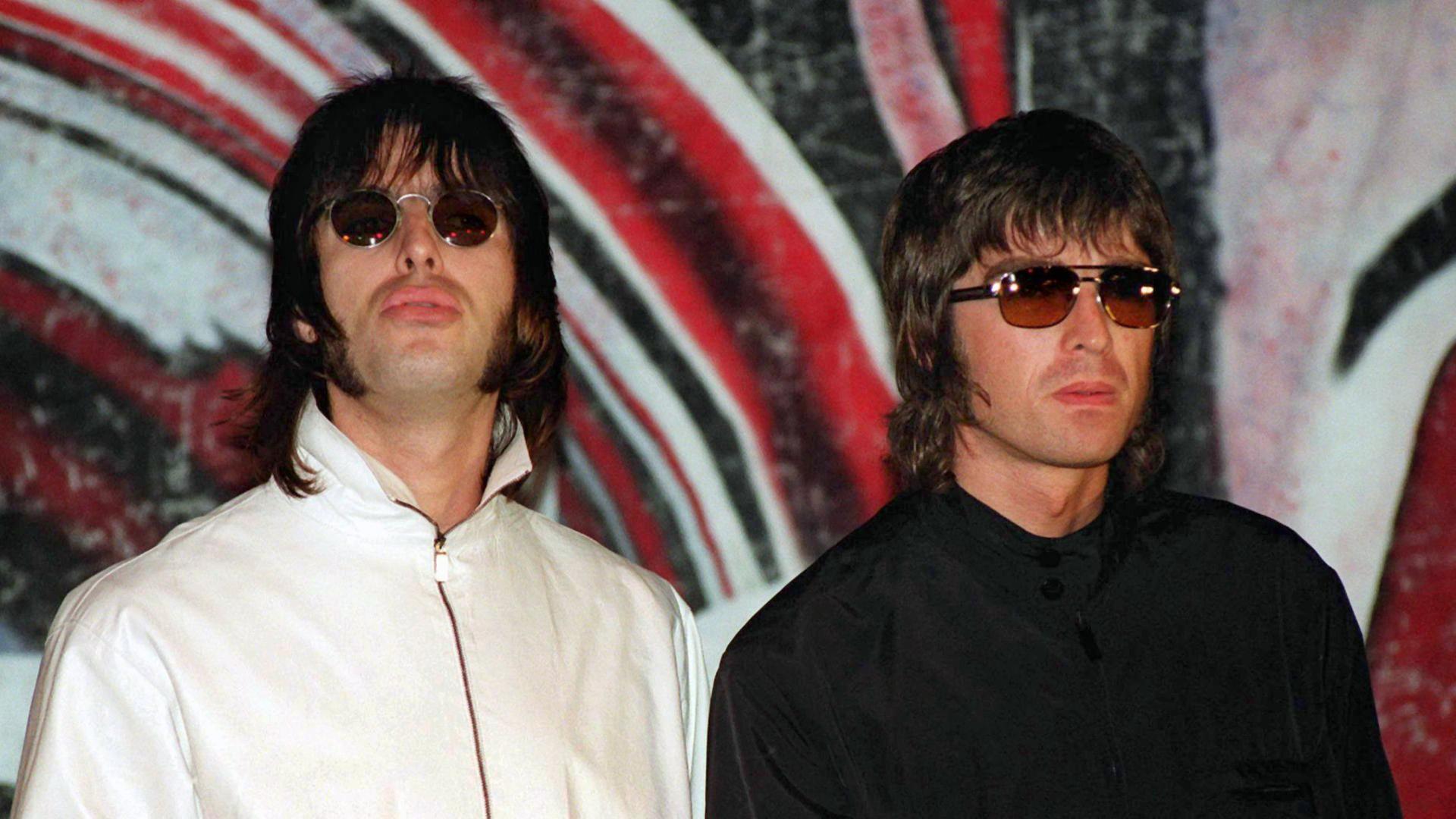 Liam (l.) und Noel Gallagher von der britischen Rockband Oasis bei einer Pressekonferenz 1999 in London, wo sie bekanntgaben, dass Bassist Paul "Guigsy" McGuigan angekündigt habe, die Band zu verlassen.