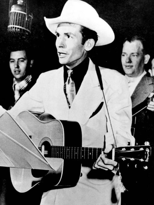 Der Musiker Hank Williams mit Gitarre und Cowboyhut bei einem Auftritt.
