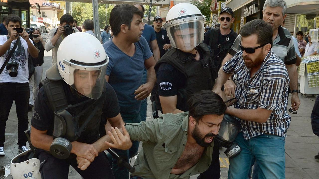 Polizisten halten am 23.07.2017 in Ankara (Türkei) einen Demonstranten fest, der zwei infahftierte Akademiker im Hungerstreik unterstützt. Sein Gesicht ist verzerrt vor Wut oder Schmerzen.