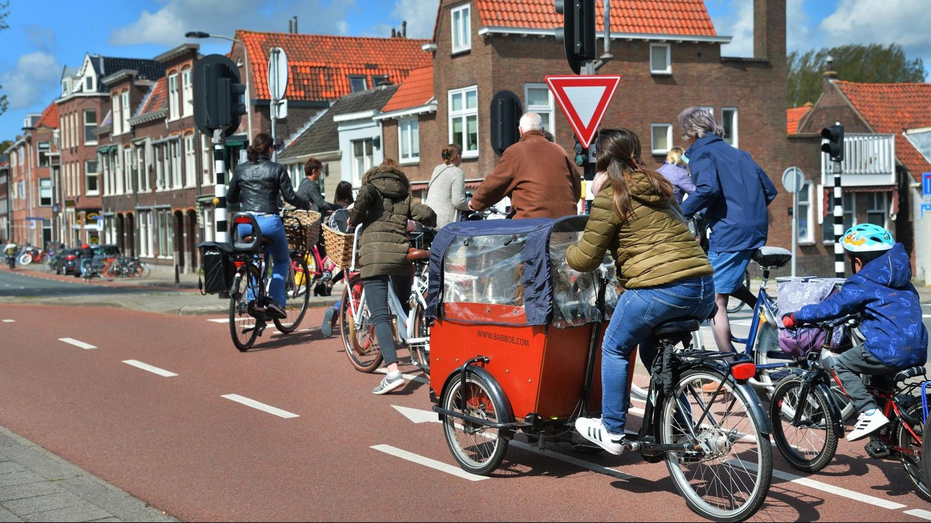 Eine Straßenszene aus den Niederlanden, die Radfahrende unterschiedlichen Alters auf einem großzügig angelegten Radweg zeigt.