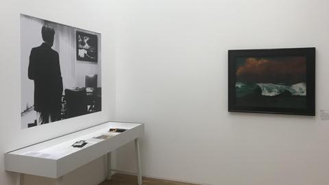 Ausstellungsansicht: Ein Foto von Helmut Schmidt im Bonner Kanzleramt mit "seinem" Nolde "Meer III" und daneben der "Brecher" von 1936 aus dem Amtszimmer von Angela Merkel. Die Ausstellung "Emil Nolde - Eine deutsche Legende. Der Künstler im Nationalsozialismus", 12.4. – 15.9.2019, Hamburger Bahnhof - Museum für Gegenwart Berlin