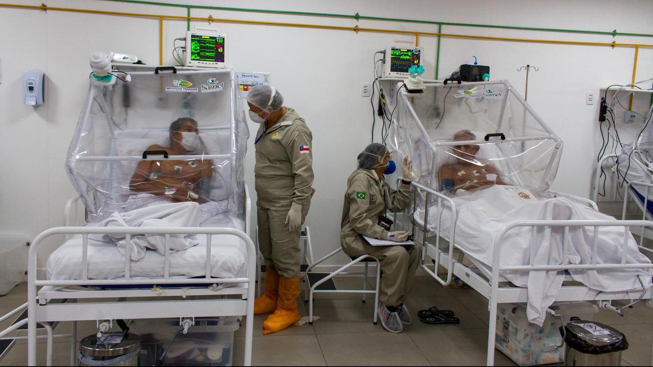 Brasilien, Manaus: Krankenpfleger unterhalten sich mit Patienten auf der Intensivstation im Gilberto Novaes Municipal Field Hospital. Das Feldkrankenhaus wurde in einer Schule eingerichtet.