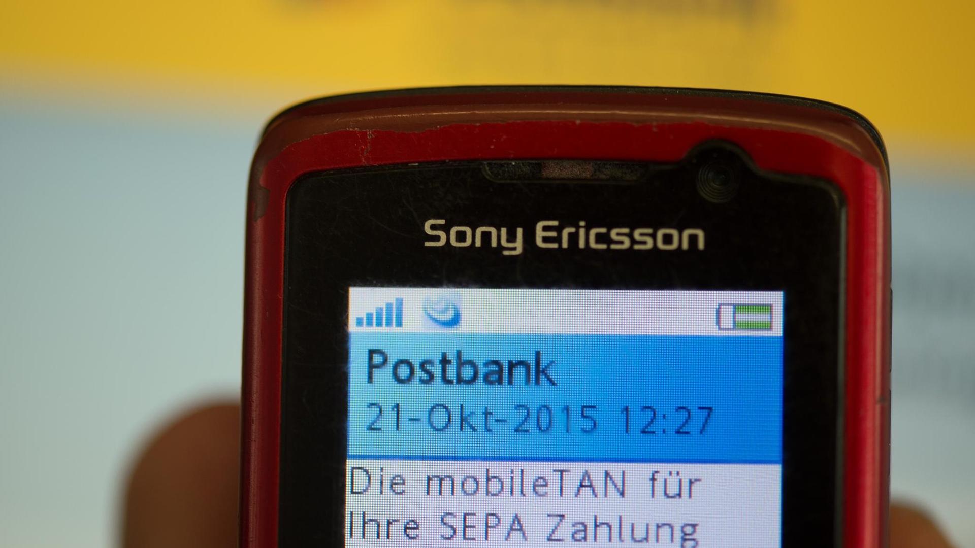 Ein Kunde der Postbank liest auf seinem Handy eine mobileTan ab.