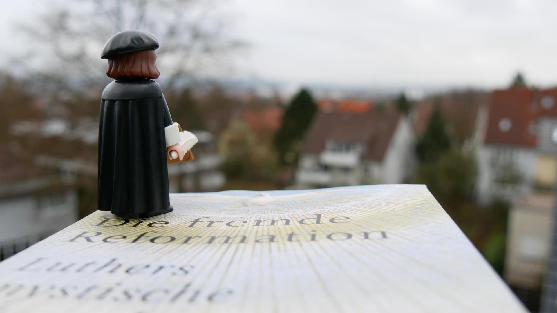 Eine Lutherfigur steht auf Volker Leppins Buch "Die fremde Reformation" und blickt in die Ferne.