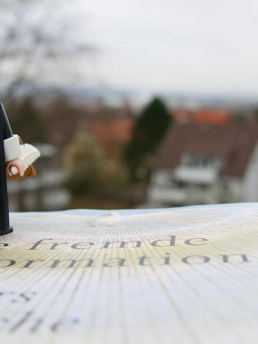 Eine Lutherfigur steht auf Volker Leppins Buch "Die fremde Reformation" und blickt in die Ferne.
