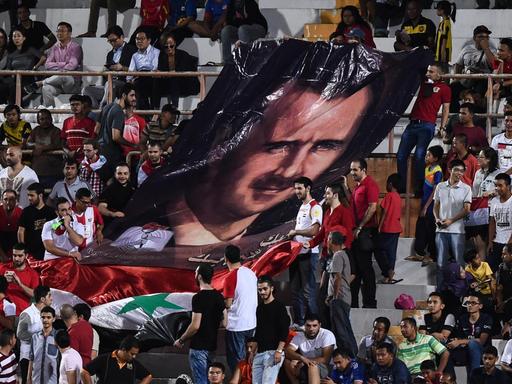 Syrische Fußballfans zeigen ein Porträt des syrischen Präsidenten Bashar al-Assad während des Qualifikationsfußballspiels der Fußball-Weltmeisterschaft 2018 zwischen Südkorea und Syrien (Archivbild 2016)