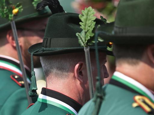 Drei Schützen in Uniformen marschieren beim Neusser Schützenfest.
