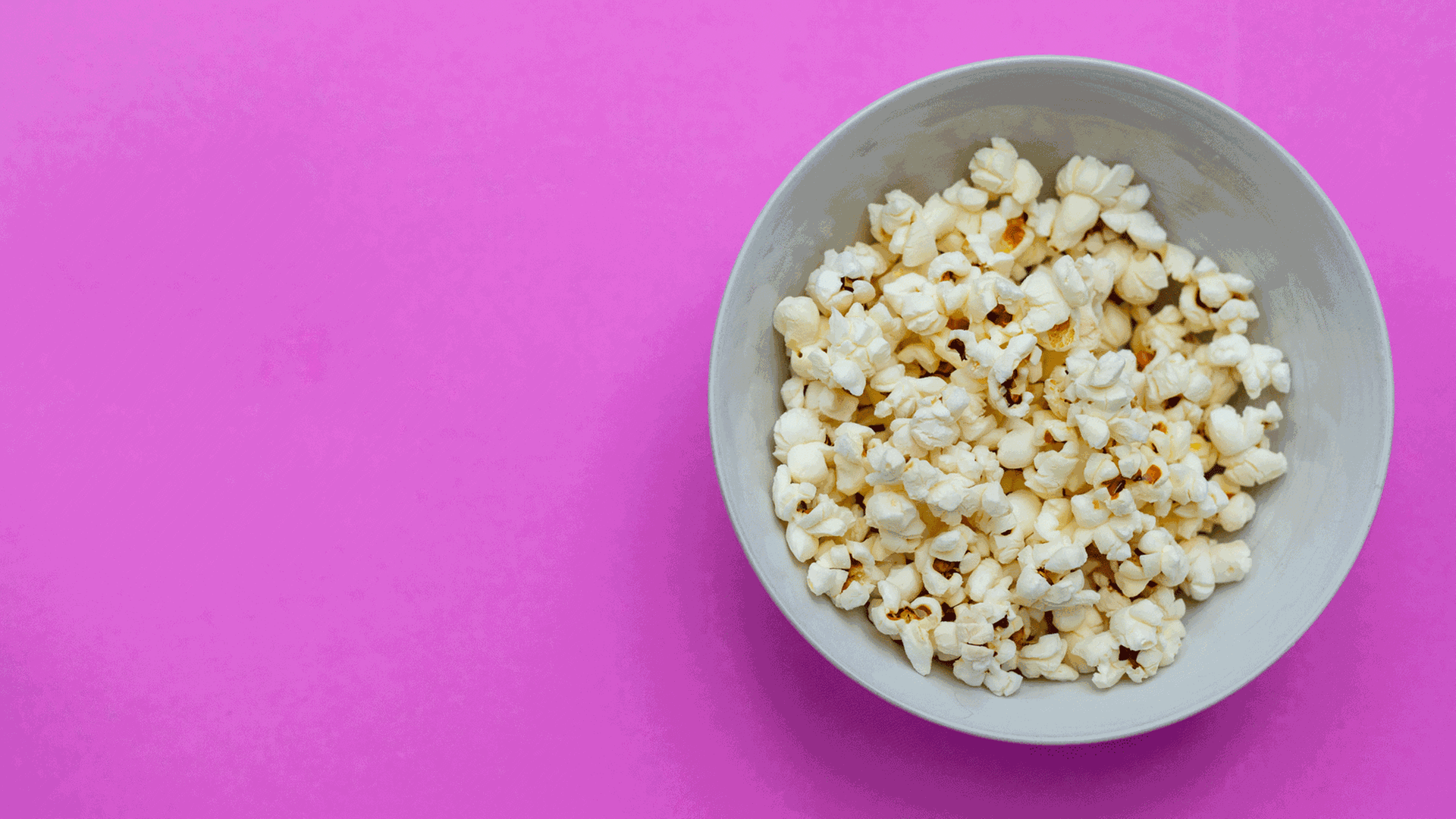 Schale mit Popcorn auf lila Hintergrund.
